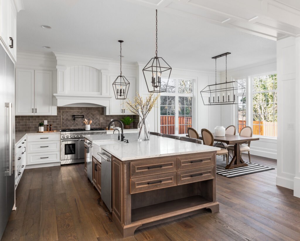 Kitchen remodeling in Sherman Oaks: a white kitchen with a marble island and pendant lighting, by Athenian Builders Group